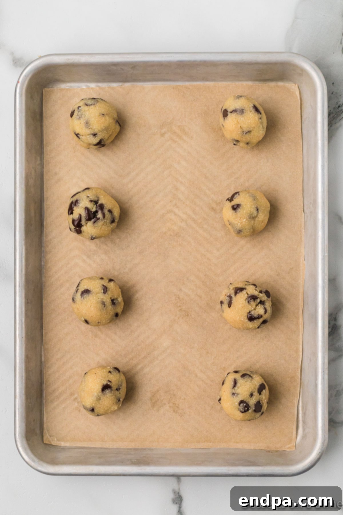 Keto Cookie Dough Bliss 7 Individual portions of keto edible cookie dough are rolled into balls and placed on a baking sheet, ready for refrigeration.