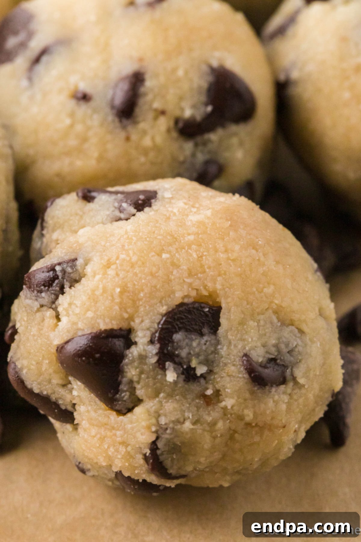 Keto Cookie Dough Bliss 8 Close-up photo of perfectly formed keto edible cookie dough balls, showcasing their delicious texture and the inviting chocolate chips within.