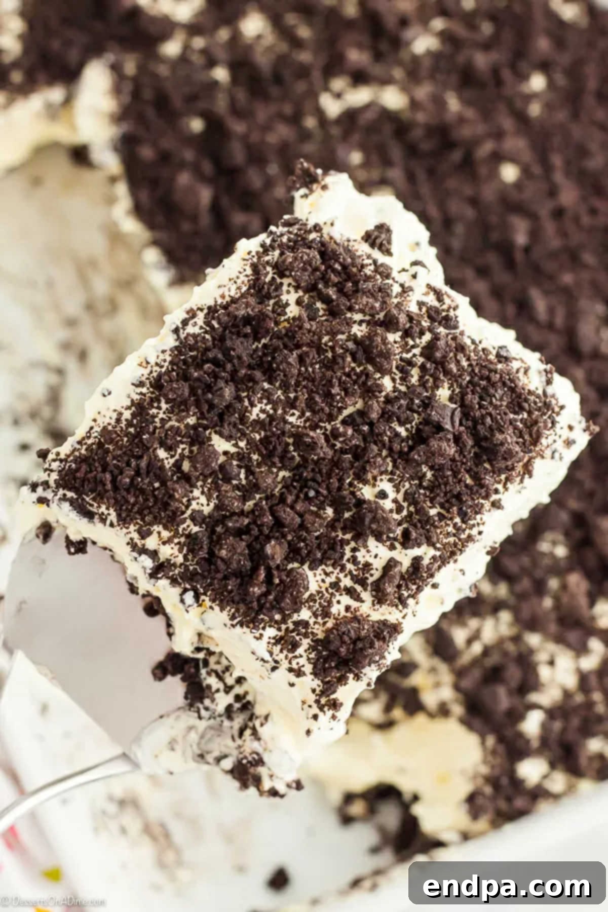 A beautifully layered Oreo Dirt Cake with a serving on a spatula, showcasing its rich textures and chocolatey goodness.
