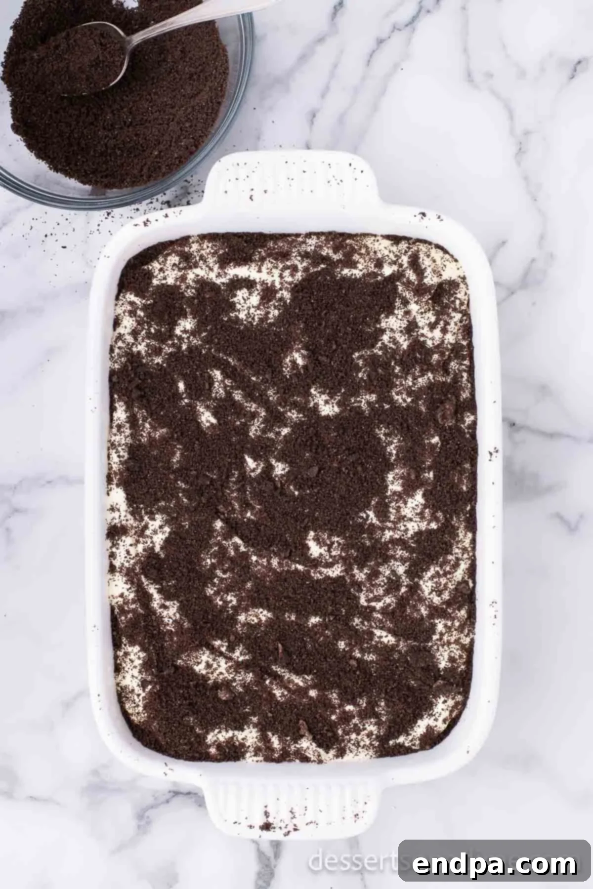 Remaining Oreo crumbs sprinkled on top of the creamy dirt cake layer, completing the 'dirt' effect.