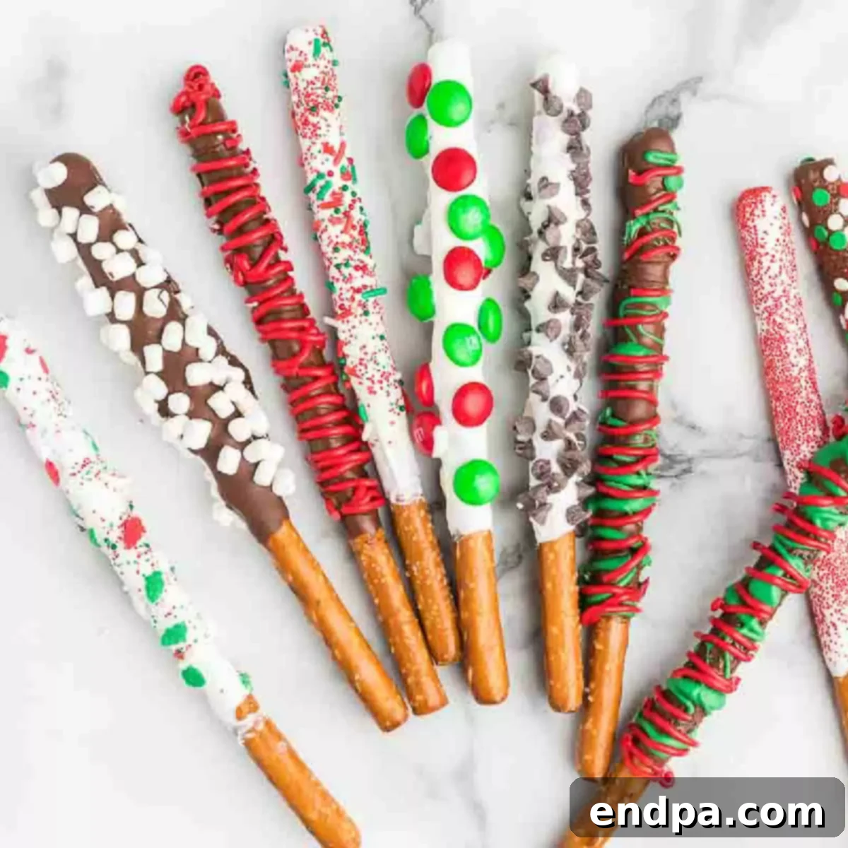 A high-angle shot of a platter filled with freshly made Christmas Chocolate Covered Pretzel Rods, adorned with various festive sprinkles and candy melt drizzles.