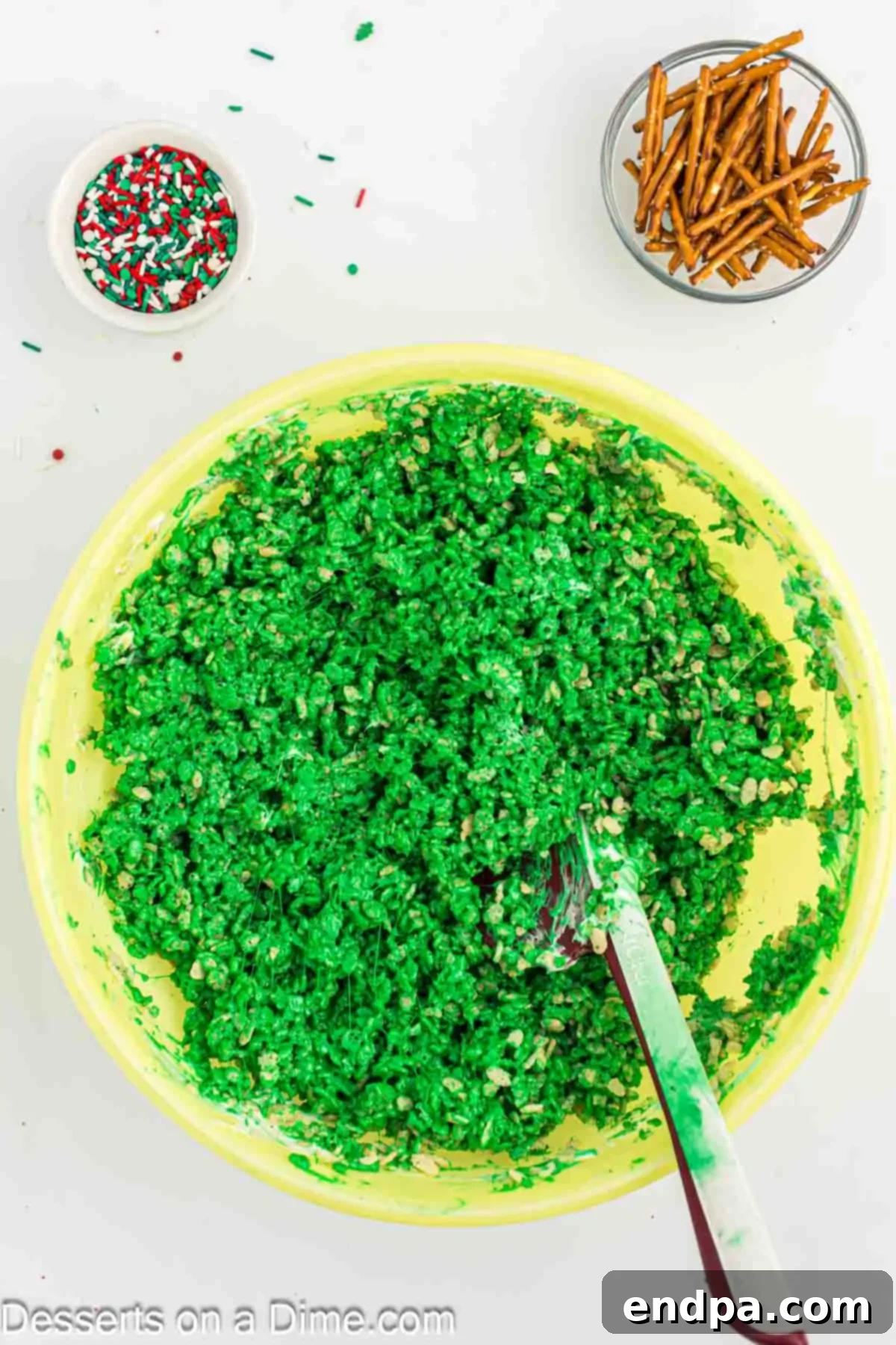 Rice Krispies cereal being added to the green marshmallow mixture in a bowl.