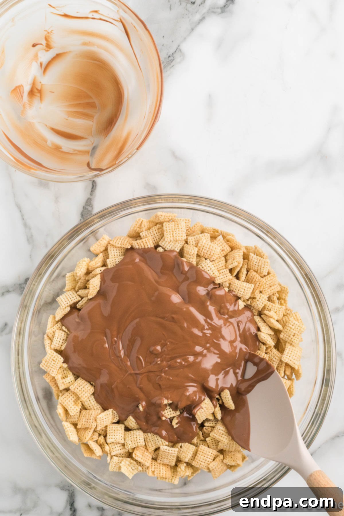 Melted chocolate and peanut butter mixture being poured over Chex cereal.