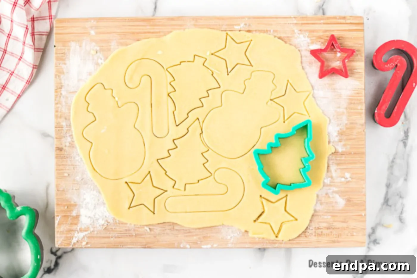 Rolled cookie dough with various Christmas cookie cutters nearby.