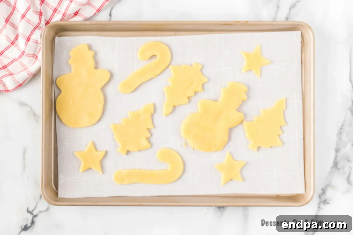 Unbaked Christmas tree and star cookies placed on a baking sheet lined with parchment paper.