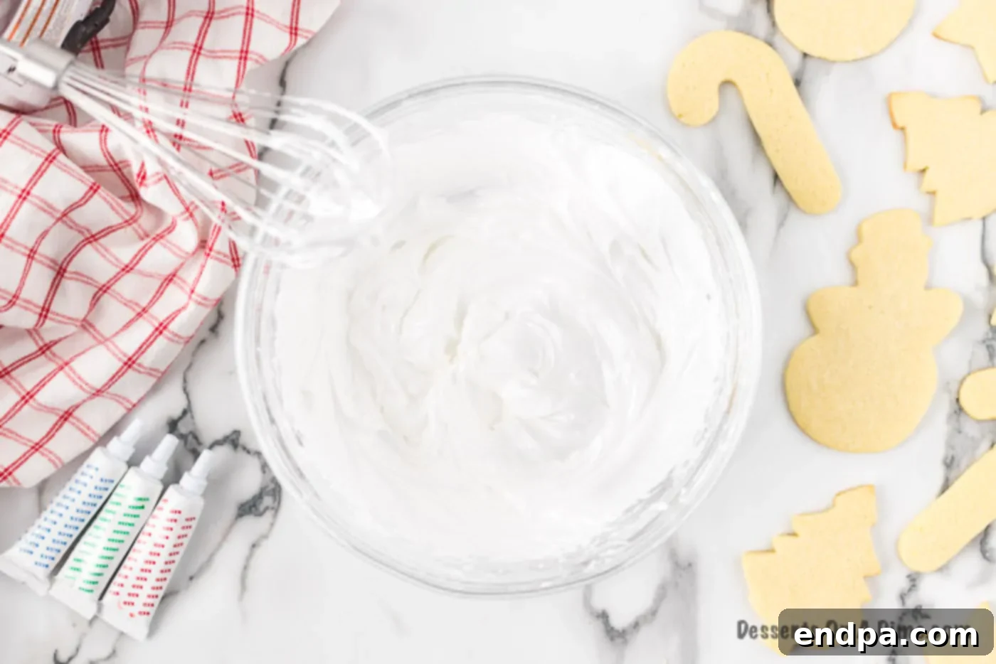 Bowl of white icing with a beater, ready to be mixed.