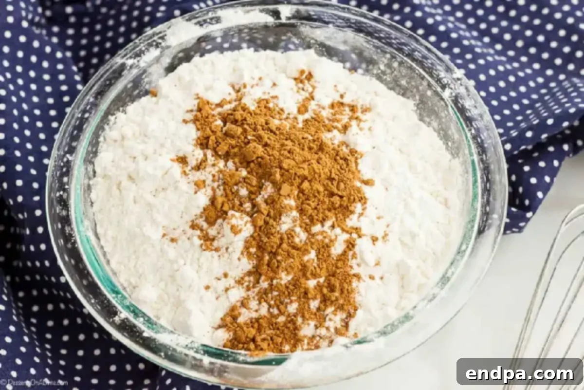 Dry yellow cake mix and apple pie spice whisked together in a bowl, ready to be sprinkled.