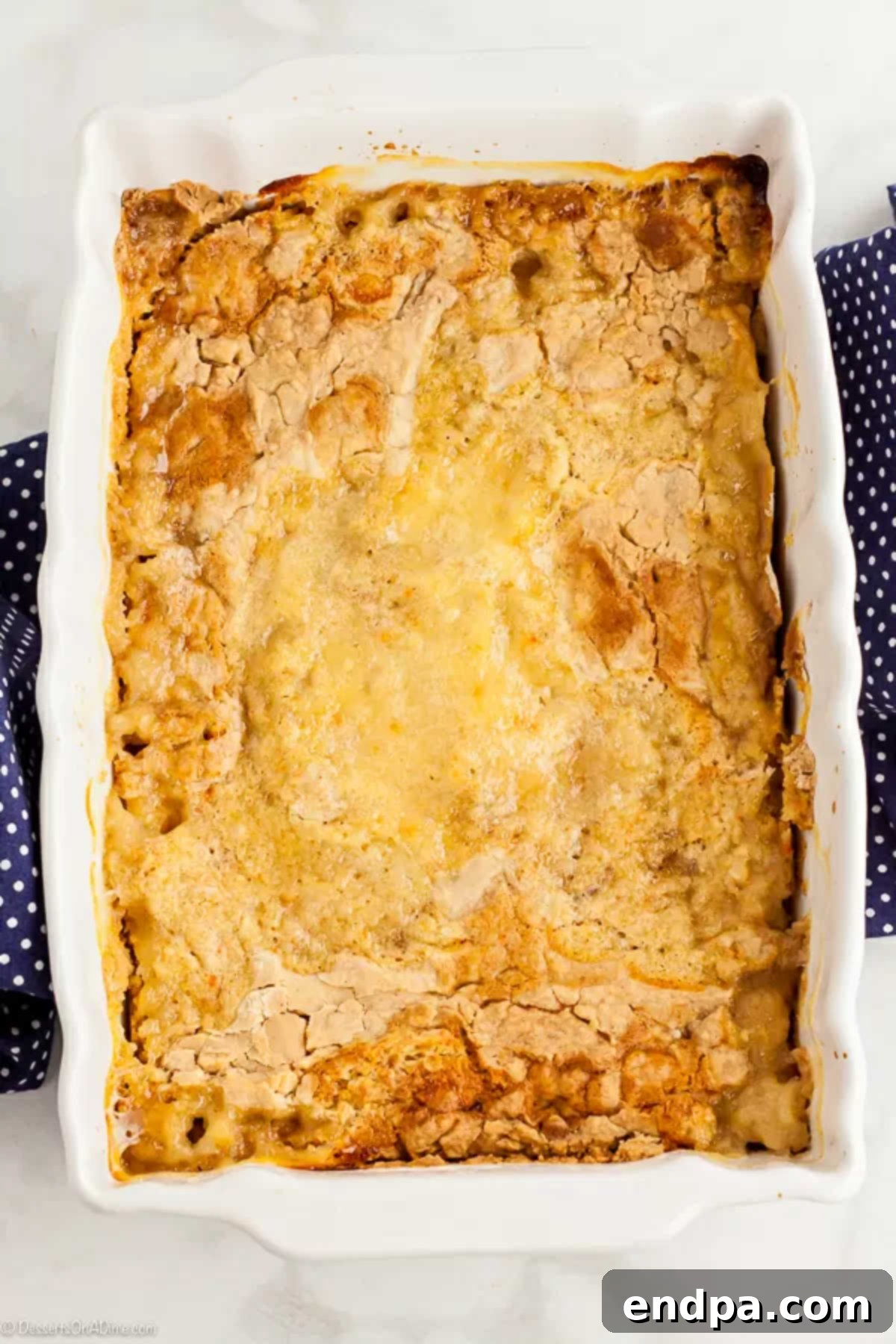 A golden-brown peach dump cake in a baking dish, freshly removed from the oven and cooling.