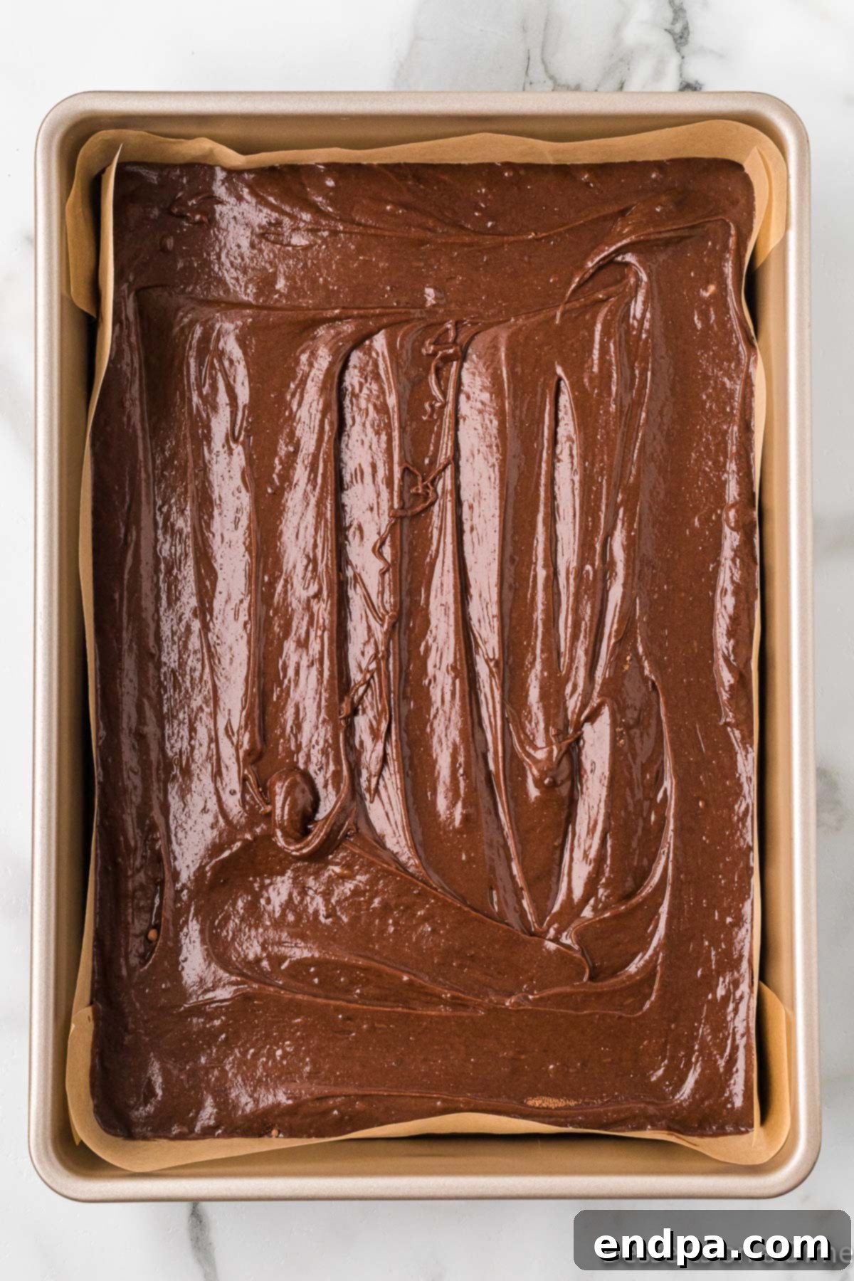 Sweetheart Brownies 6 Smooth brownie batter poured evenly into a parchment-lined baking pan.