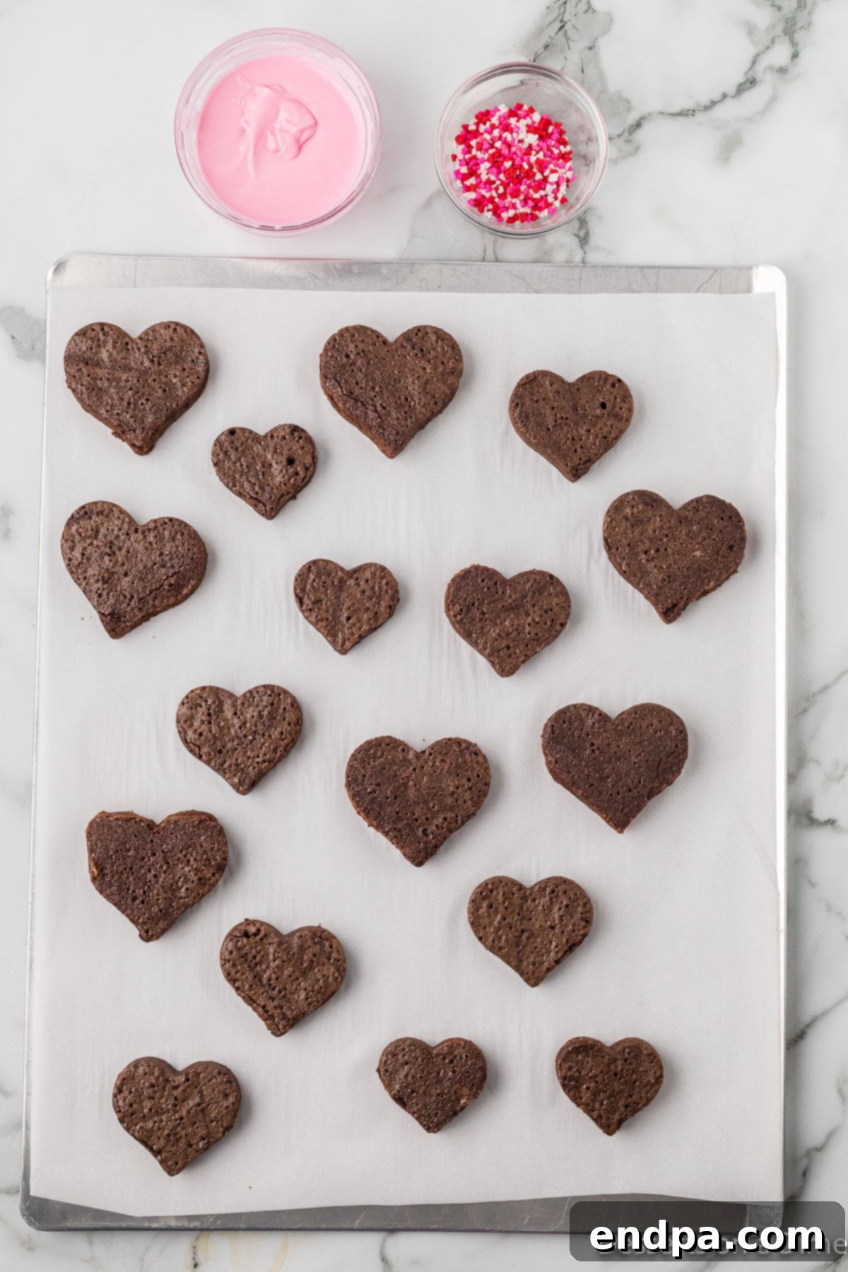 Sweetheart Brownies 8 Baked brownies on a cutting board with heart shapes cut out using a cookie cutter.