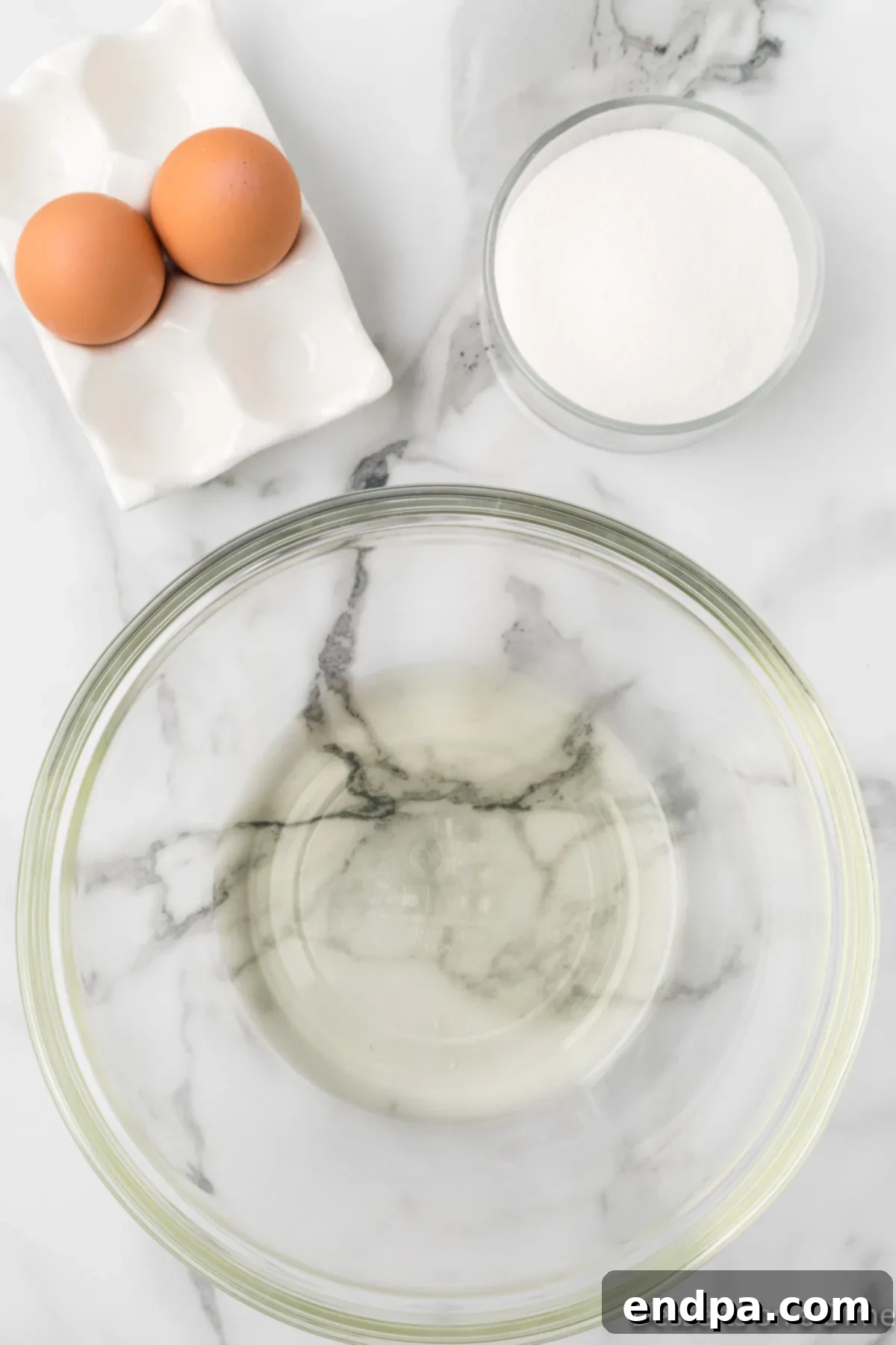A mixing bowl containing vegetable oil, eggs, and granulated sugar, ready to be combined.