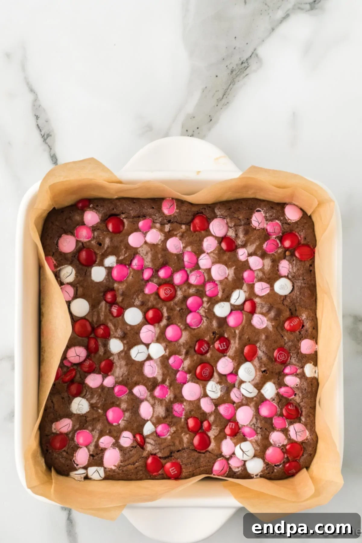 Baked Valentine's Day Brownies in the pan, fresh out of the oven, with a crackled top and melted M&Ms.