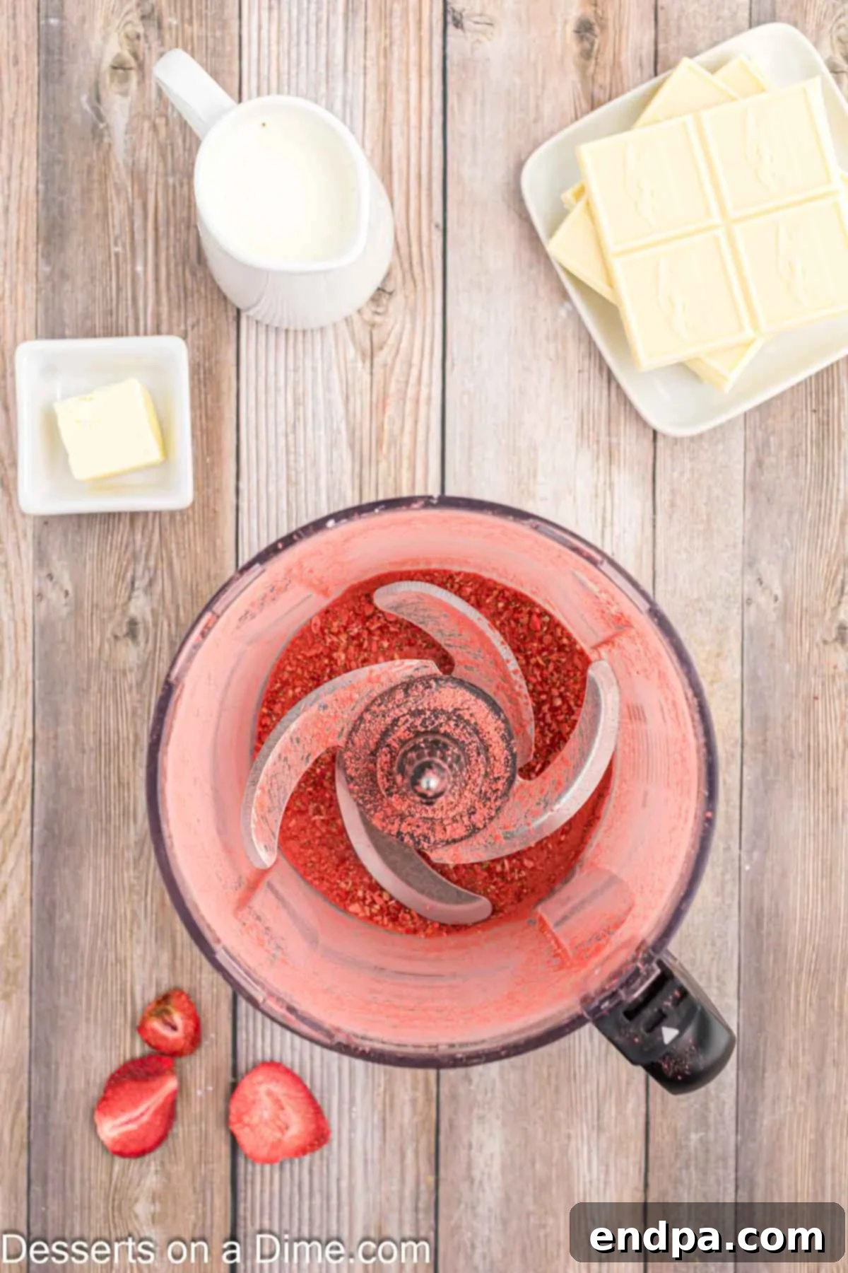 Freeze-dried strawberries being processed into fine powder in a food processor.