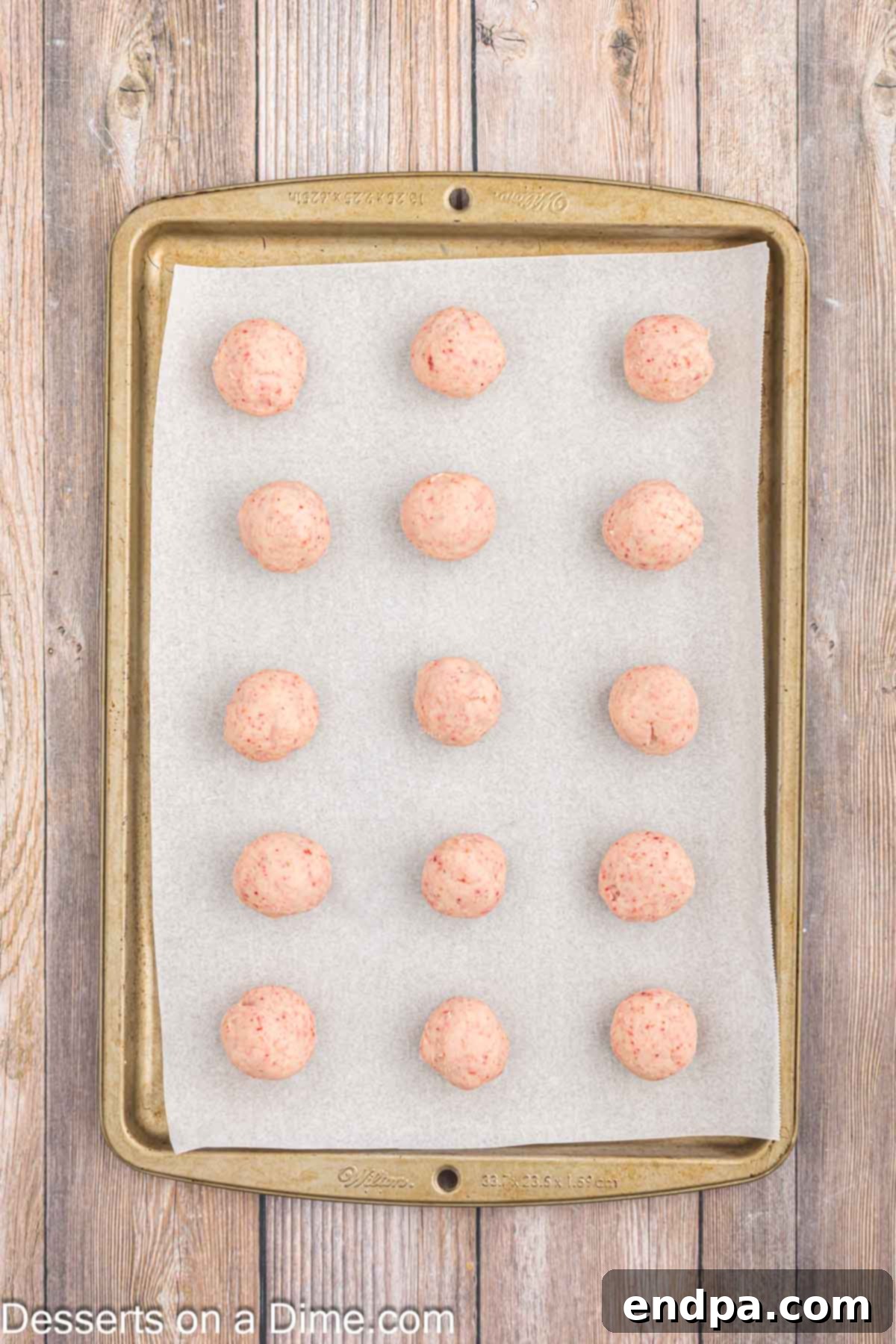 Formed strawberry truffle balls placed on wax paper, ready for freezing.