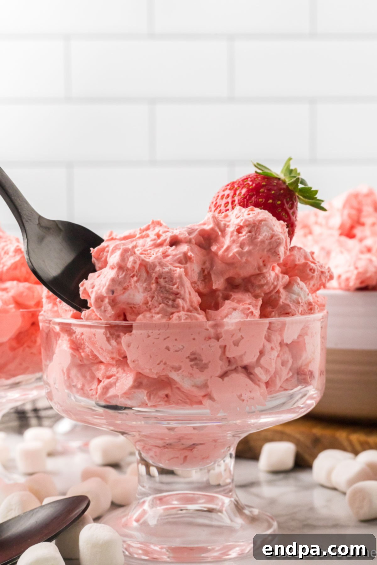 Strawberry Cloud Delight 2 A vibrant Strawberry Fluff Salad presented beautifully in a glass serving dish, garnished with fresh strawberries, ready to be enjoyed.