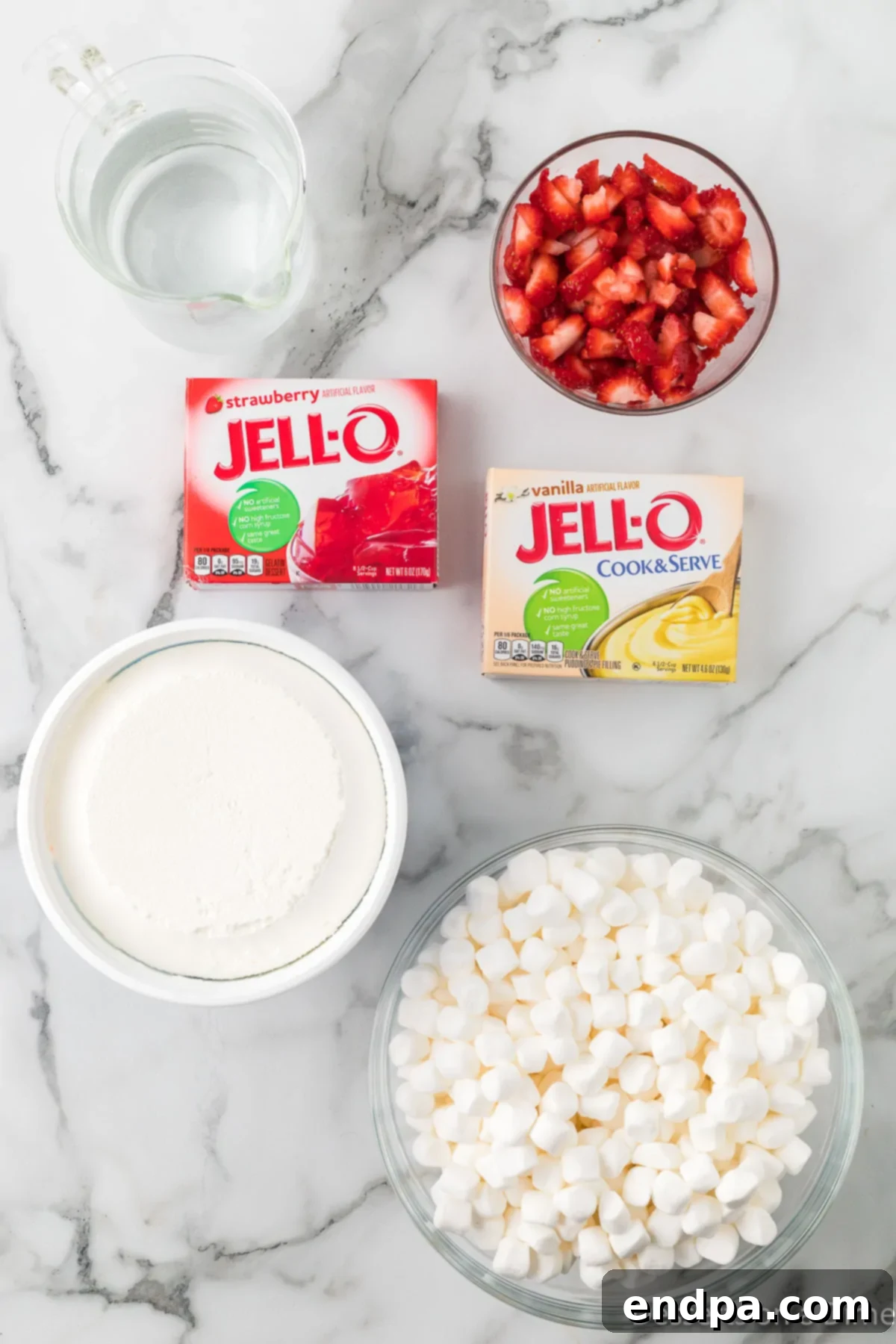 Strawberry Cloud Delight 3 A flat lay image showcasing the five core ingredients for Strawberry Fluff Salad: vanilla pudding mix, strawberry jello mix, whipped topping, mini marshmallows, and fresh, diced strawberries.