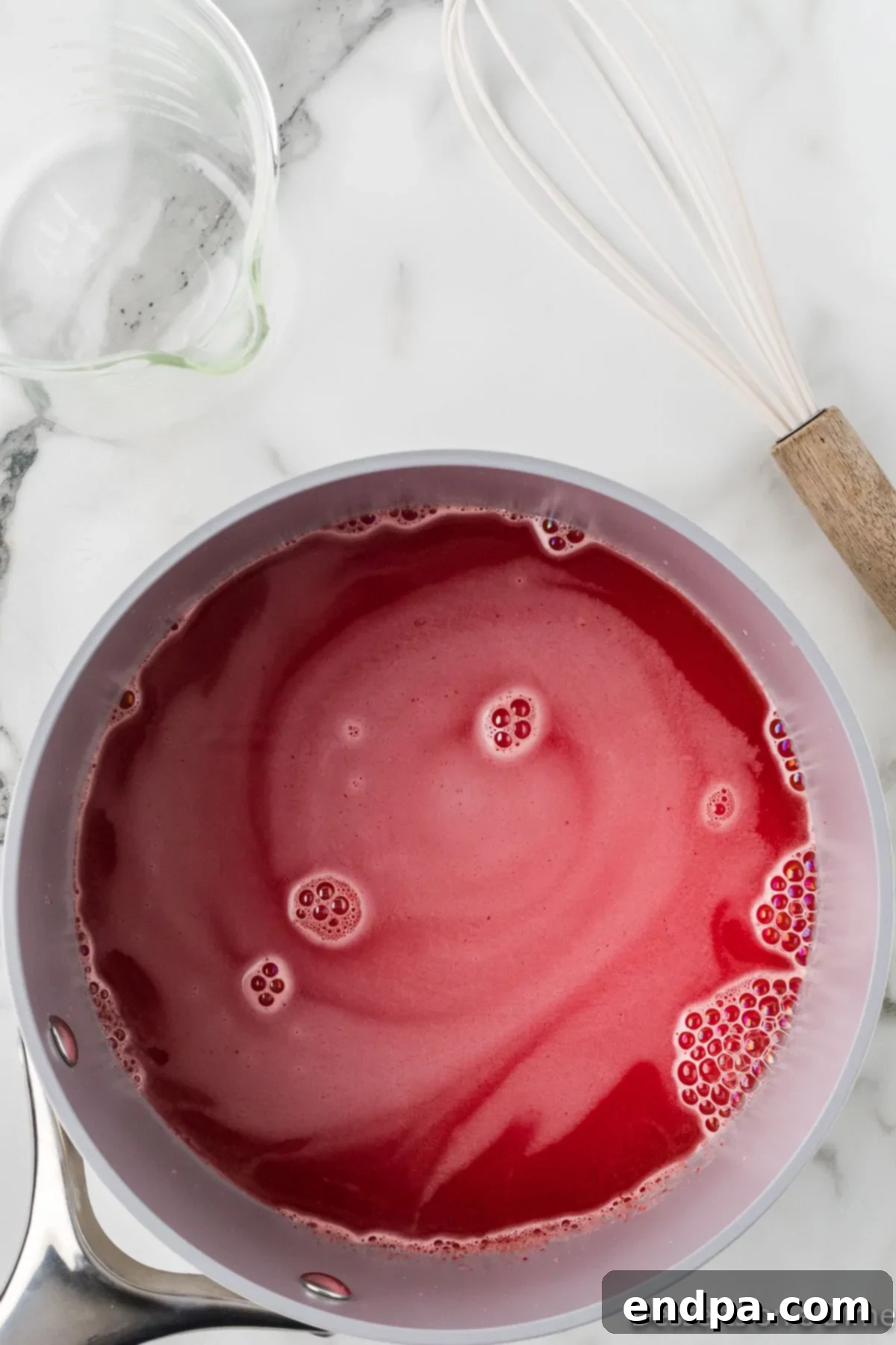 Strawberry Cloud Delight 4 Strawberry jello and vanilla pudding mixture simmering in a medium saucepan on the stovetop, just before boiling.