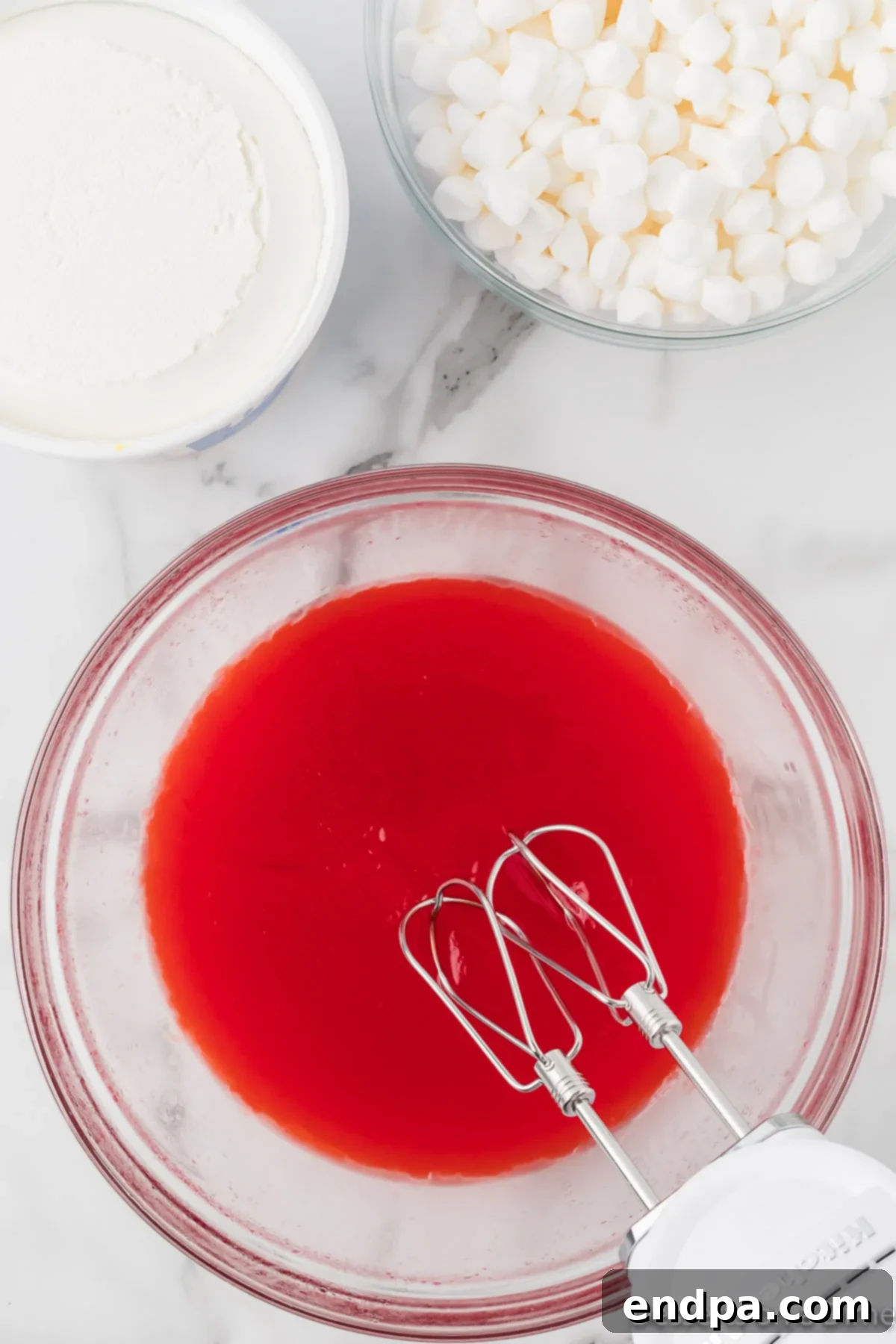 Strawberry Cloud Delight 5 Thickened jello and pudding mixture in a large heat-resistant bowl, being beaten with an electric mixer until creamy and smooth.