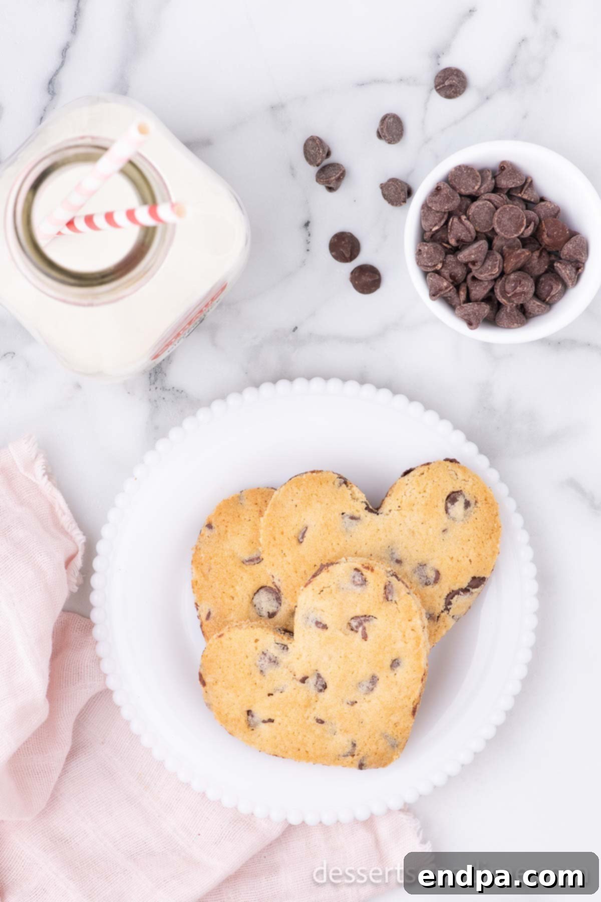 Heartfelt Chocolate Chip Bites 11 Heart-shaped chocolate chip cookies served on a plate with a glass of milk, a perfect snack or dessert.