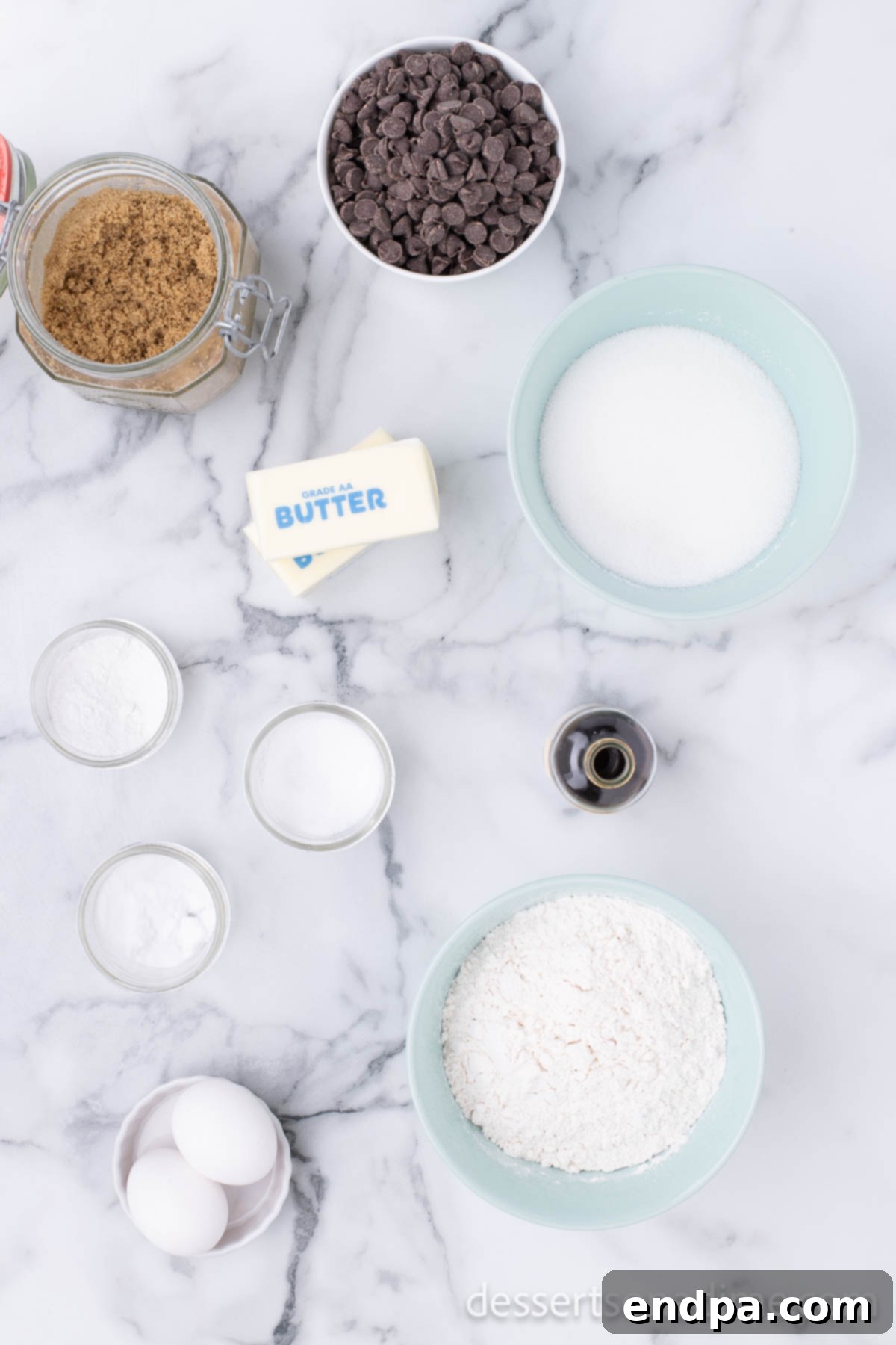 Heartfelt Chocolate Chip Bites 3 All ingredients for homemade heart-shaped chocolate chip cookies laid out on a table: butter, sugar, brown sugar, eggs, vanilla, flour, salt, baking soda, baking powder, and semi-sweet chocolate chips.