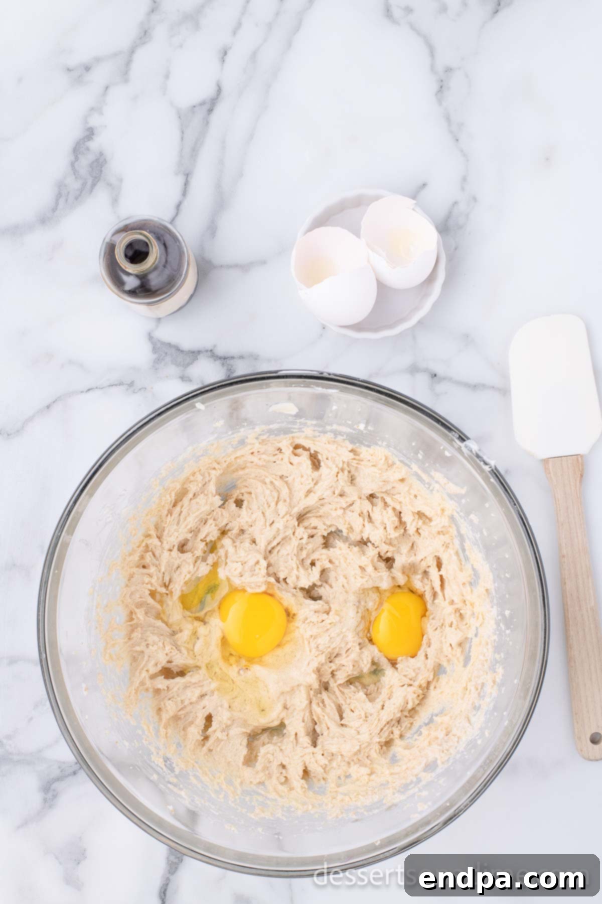 Heartfelt Chocolate Chip Bites 5 Large eggs are cracked and added to the creamed butter and sugar mixture in the bowl.