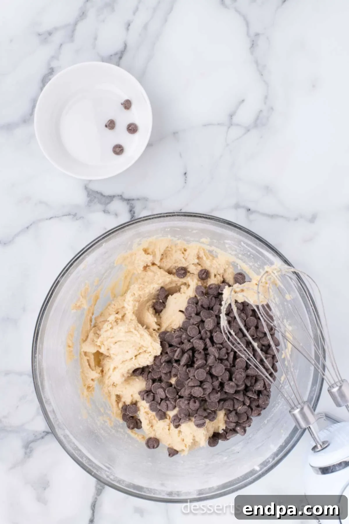 Heartfelt Chocolate Chip Bites 7 Semi-sweet chocolate chips being folded into the prepared cookie dough by hand with a spatula.
