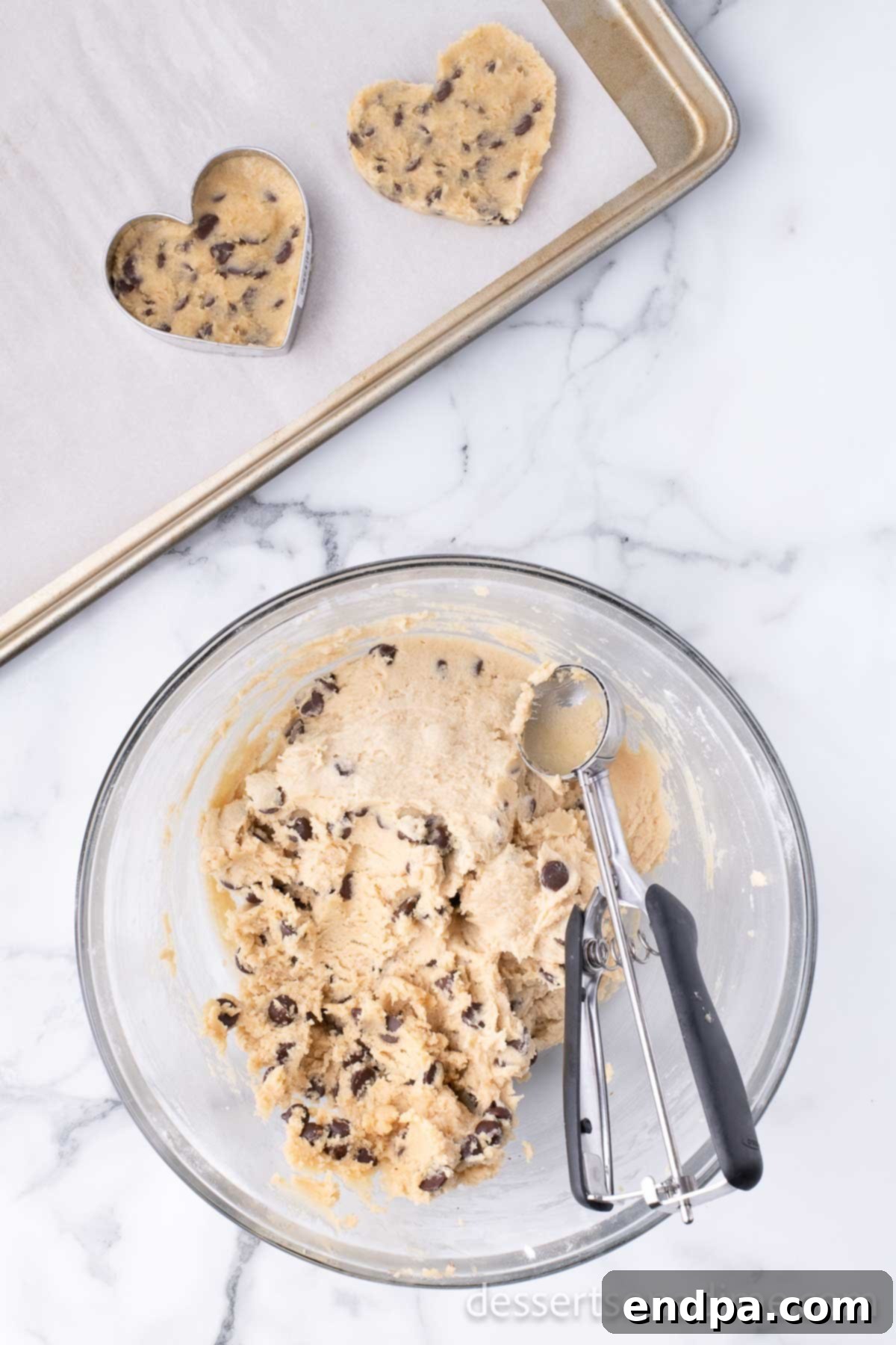 Heartfelt Chocolate Chip Bites 8 Cookie dough balls are formed and then placed inside a heart-shaped cookie cutter on a baking sheet to create perfect heart shapes.