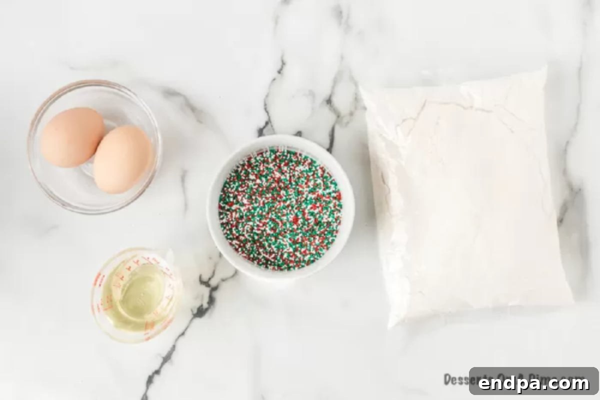 Christmas cake mix cookies make an easy and festive treat with only 4 ingredients. They are so light and fluffy for the perfect dessert. Learn how to make cake mix cookies with sprinkles. This is the best treat. Ingredients for Christmas cake mix cookies: a box of white cake mix, two eggs, a bottle of vegetable oil, and a bag of red and green Christmas sprinkles.