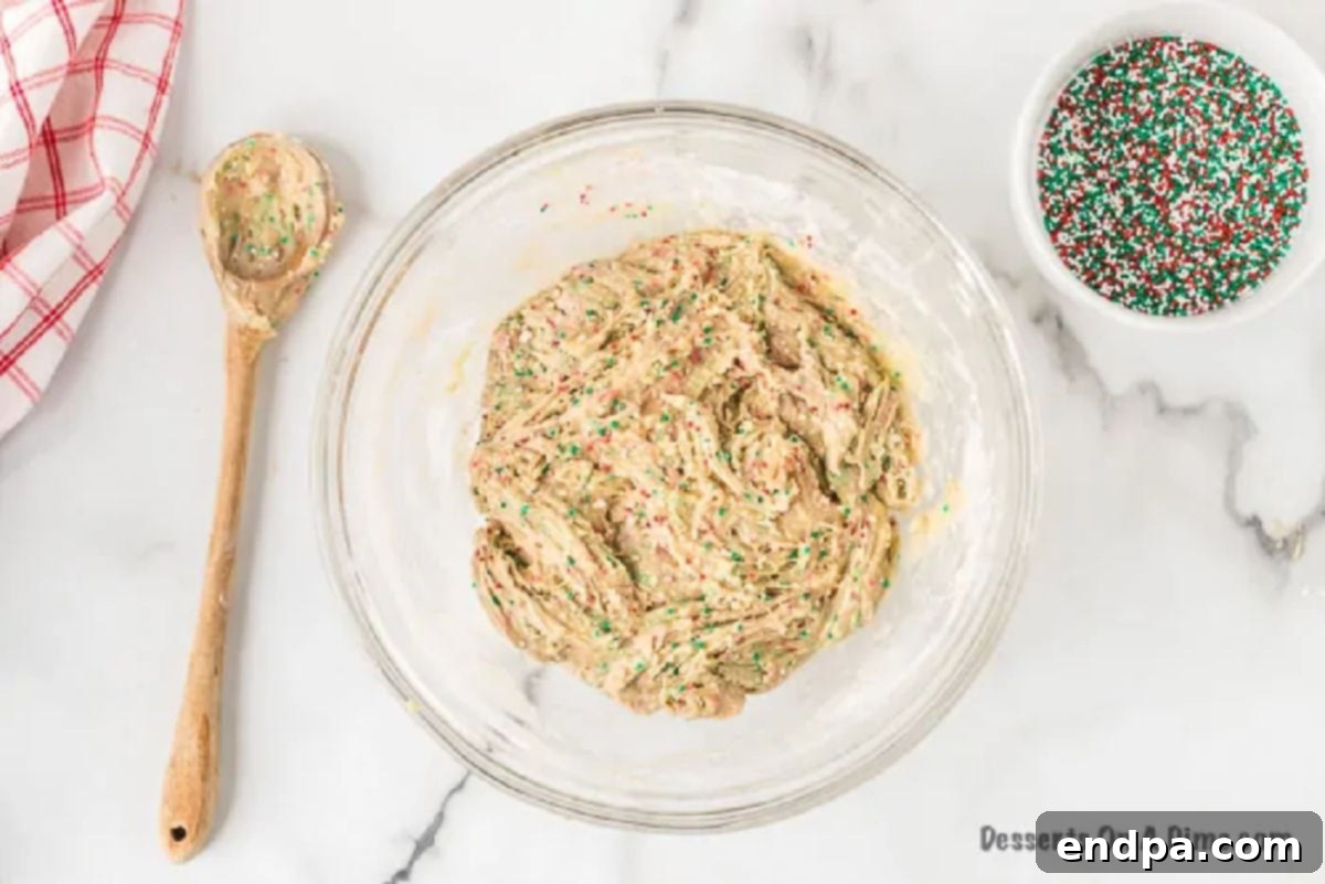 Quick and Festive Cake Mix Christmas Cookies 3 A mixing bowl containing white cake mix, eggs, vegetable oil, and a quarter cup of red and green Christmas sprinkles, after being combined.