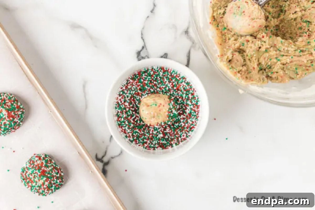 Quick and Festive Cake Mix Christmas Cookies 4 Cookie dough balls neatly rolled in a generous coating of red and green Christmas sprinkles, ready for baking.