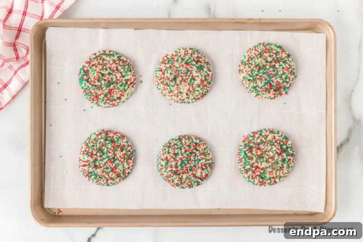 Quick and Festive Cake Mix Christmas Cookies 5 Unbaked cookie dough balls, generously coated in sprinkles, arranged on a baking sheet with ample space between them.