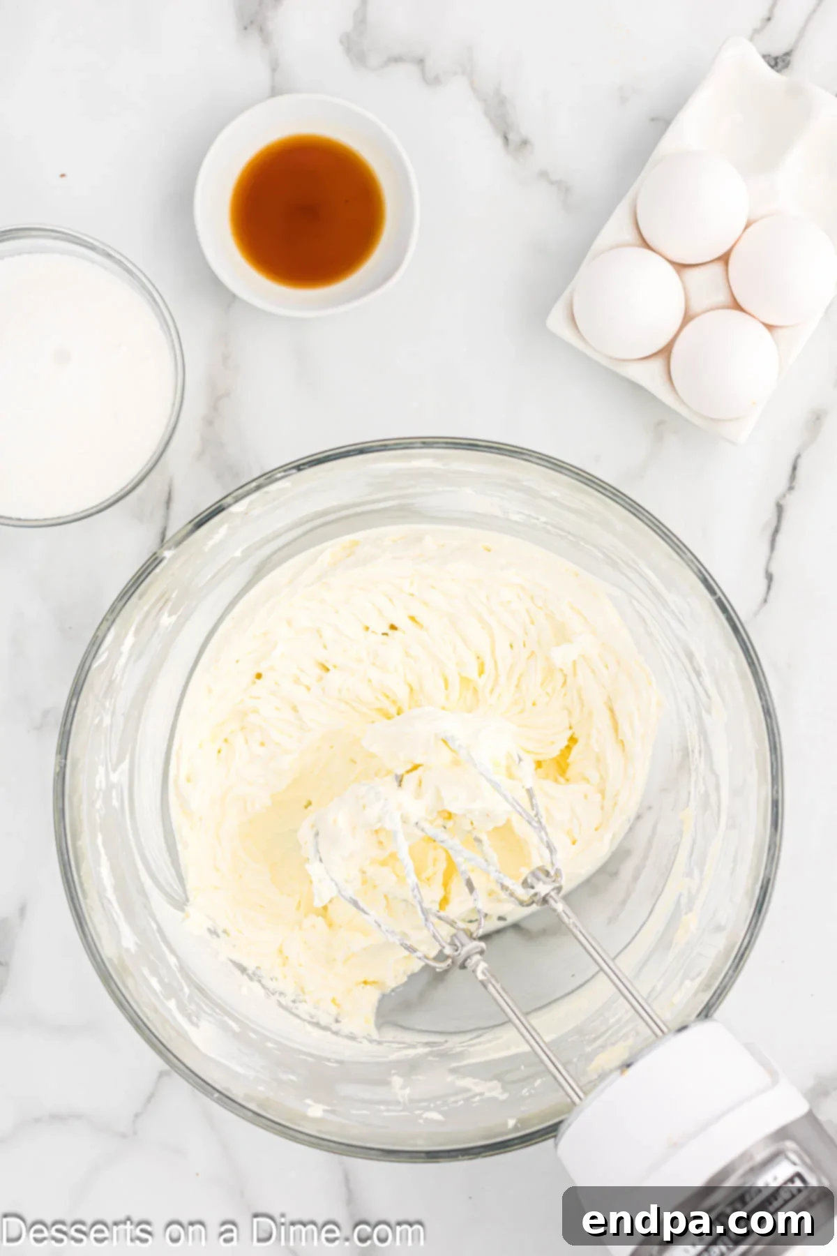 Cream cheese in bowl being beat with a mixer. 