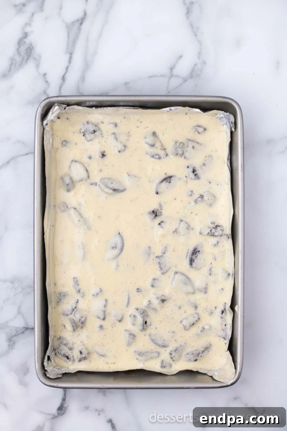 Heavenly Oreo Cheesecake Treats 10 Cheesecake mixture being poured and smoothed over the baked Oreo crust.