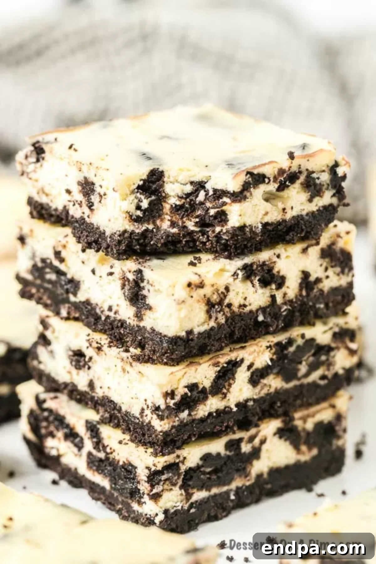 Oreo Cheesecake Bars: A delightful fusion of classic Oreo cookies and creamy cheesecake, perfect for any occasion. This easy-to-make dessert is packed with chocolatey goodness, offering a simple yet elegant treat. Enjoy these Cookies and Cream Cheesecake Bars for an unforgettable dessert. Four stacked Oreo Cheesecake Bars with one having a bite taken out of it, showcasing the layers.