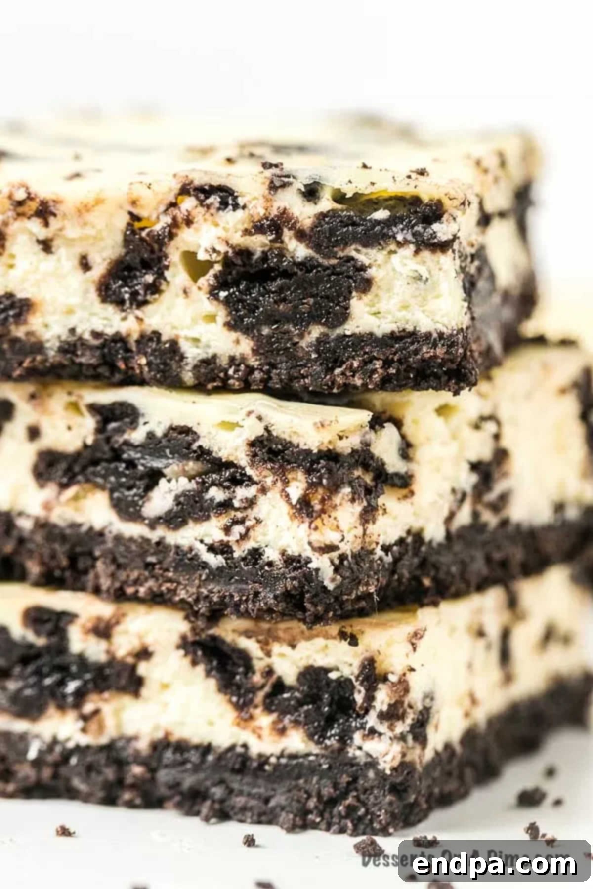 Oreo Cheesecake Bars: A delightful fusion of classic Oreo cookies and creamy cheesecake, perfect for any occasion. This easy-to-make dessert is packed with chocolatey goodness, offering a simple yet elegant treat. Enjoy these Cookies and Cream Cheesecake Bars for an unforgettable dessert. A close-up view of three stacked Oreo Cheesecake Bars, highlighting their texture and layers.