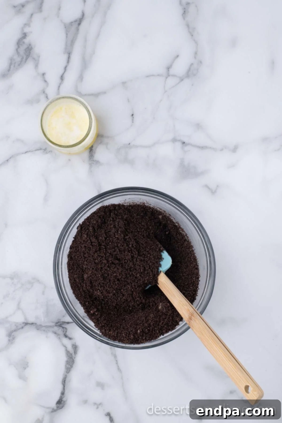 Heavenly Oreo Cheesecake Treats 3 Crushed Oreo cookies mixed with melted butter in a bowl.