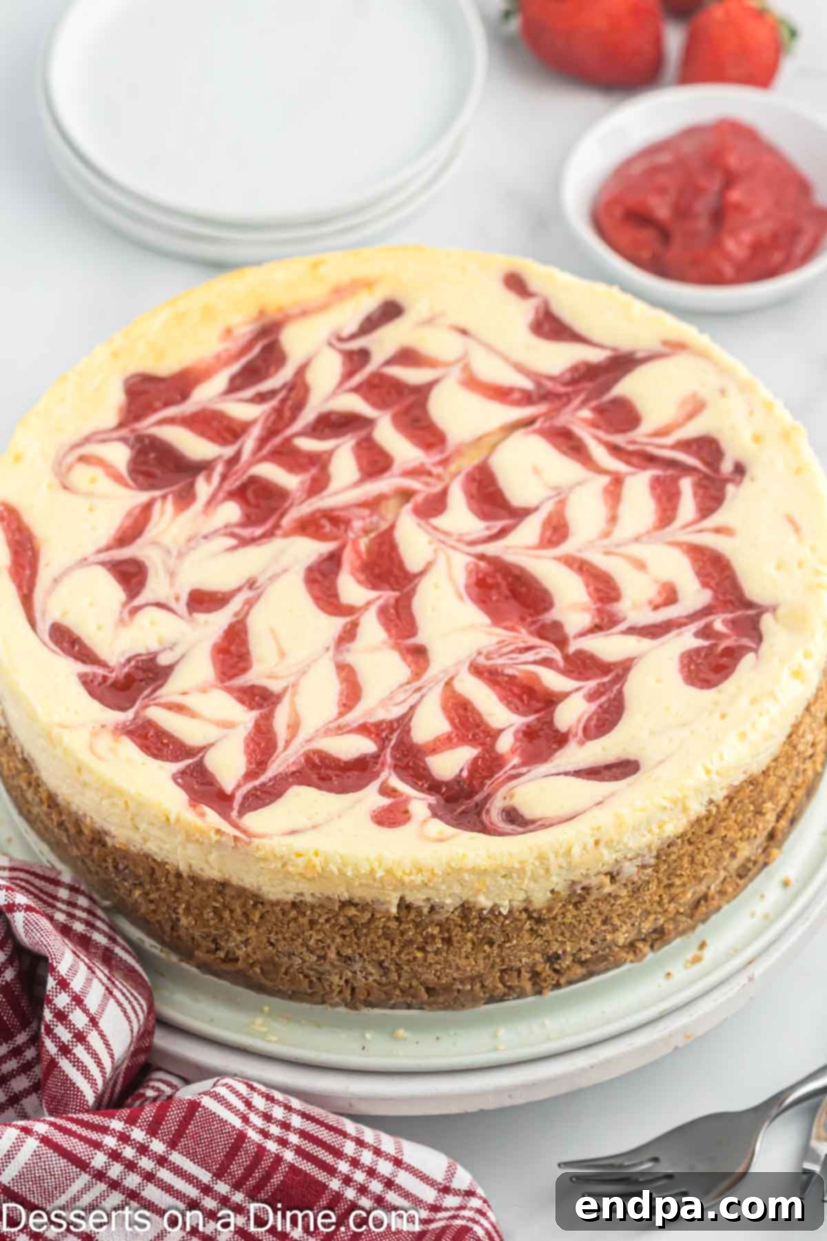 Whole strawberry swirl cheesecake ready to slice, showcasing its beautiful marbled top.