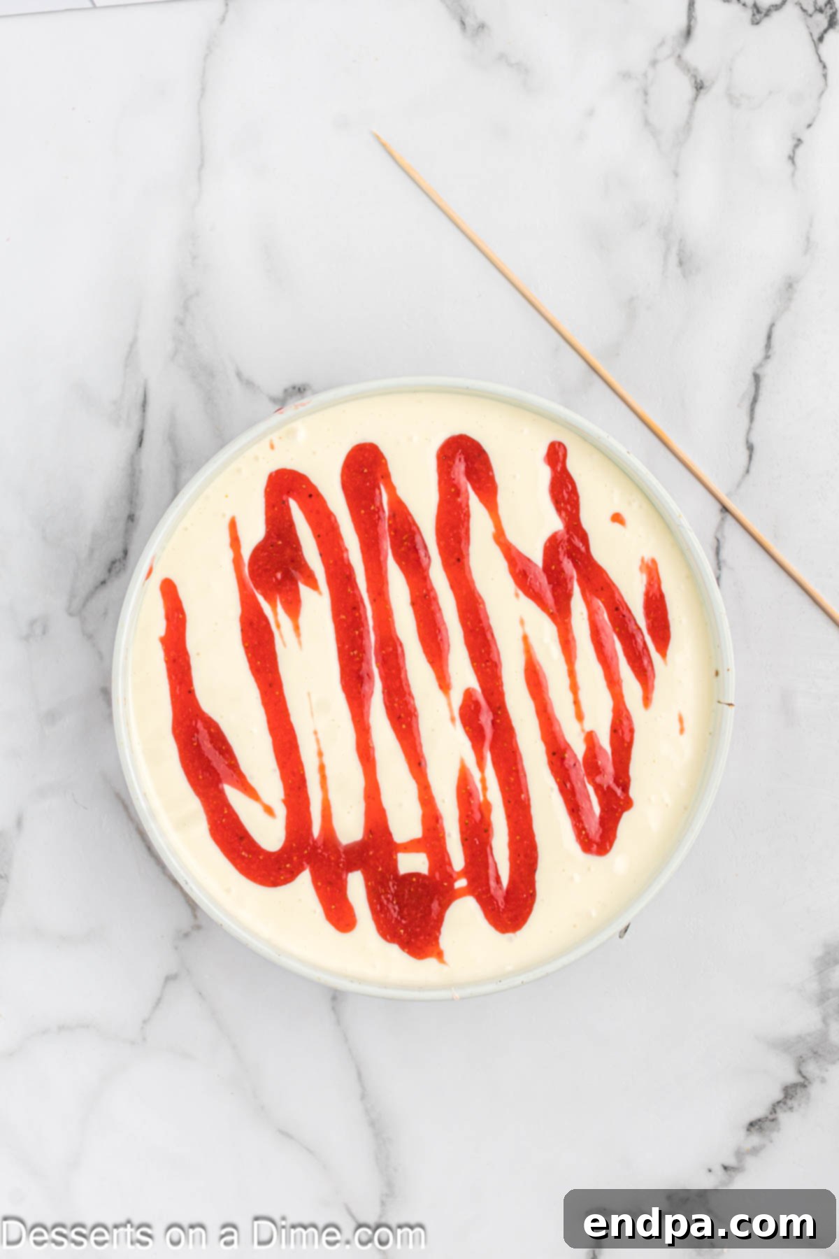 Strawberry sauce being swirled on top of the cream cheese filling.