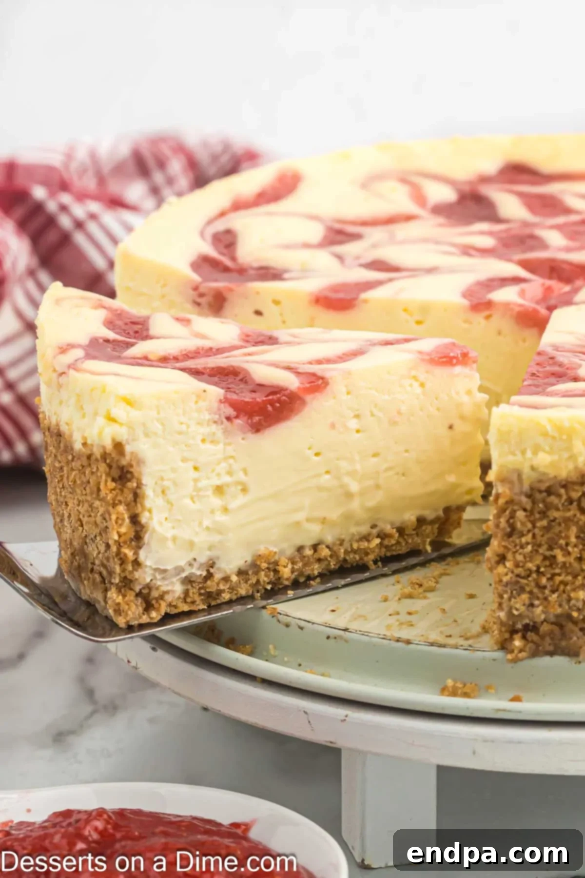 A perfect slice of strawberry swirl cheesecake on a white platter, showing the distinct layers.