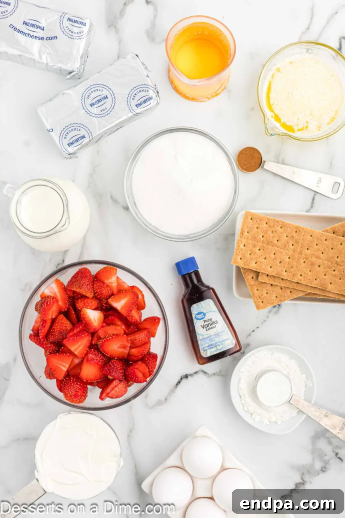 Ingredients for strawberry swirl cheesecake laid out: graham crackers, melted butter, sugar, cinnamon, fresh strawberries, cornstarch, cream cheese, vanilla extract, sour cream, eggs, heavy cream.