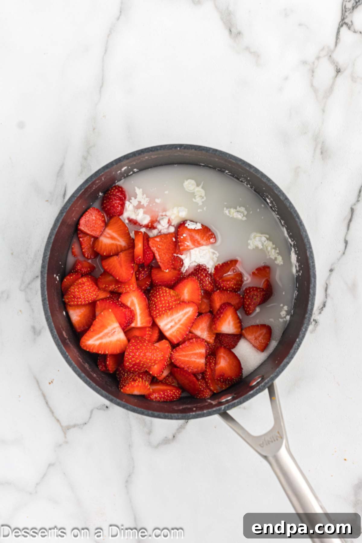 Sliced strawberries, sugar, cornstarch, and water in a saucepan for the sauce.