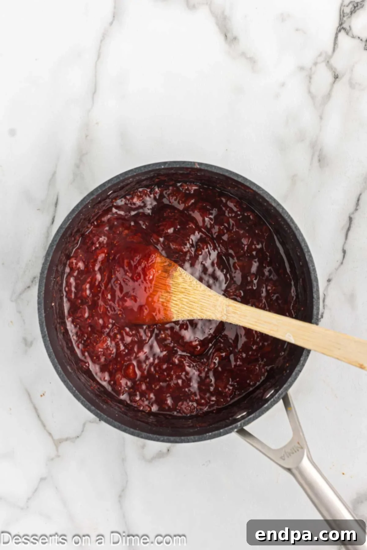 Thickening strawberry sauce simmering in a saucepan.