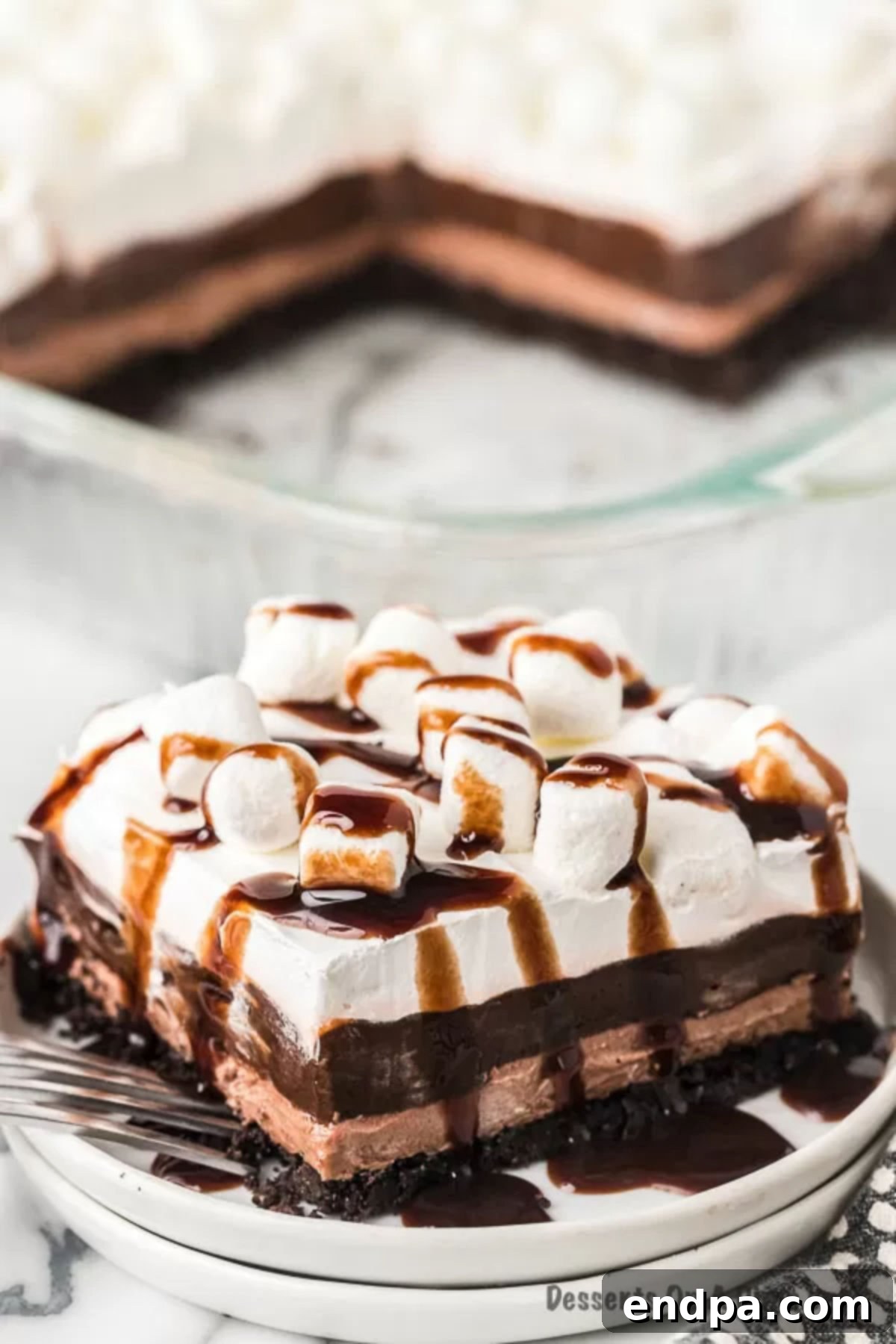 Decadent Hot Cocoa Lasagna 11 A perfectly cut slice of Hot Chocolate Lasagna presented on a white plate, showcasing its distinct layers.