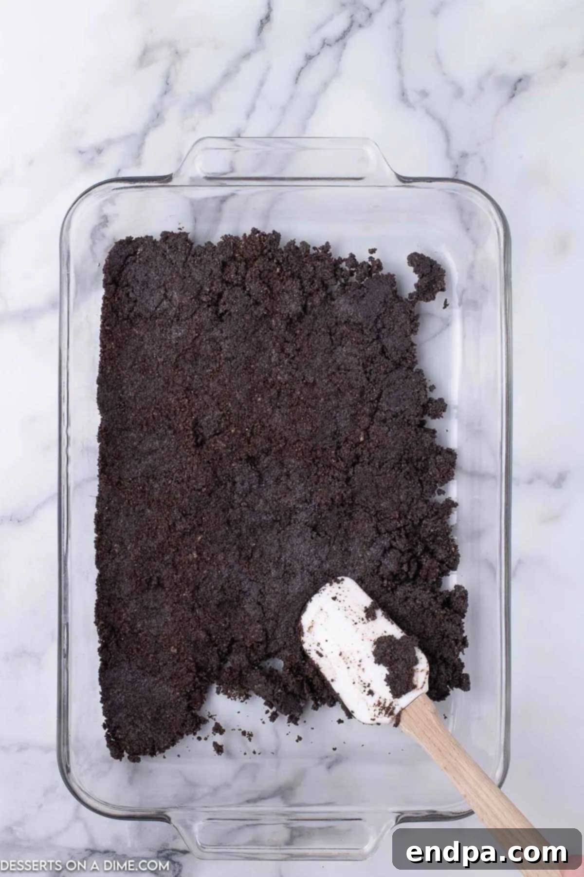 Decadent Hot Cocoa Lasagna 5 The Oreo crust mixture spread evenly into a 13x9 inch baking dish, ready for chilling.