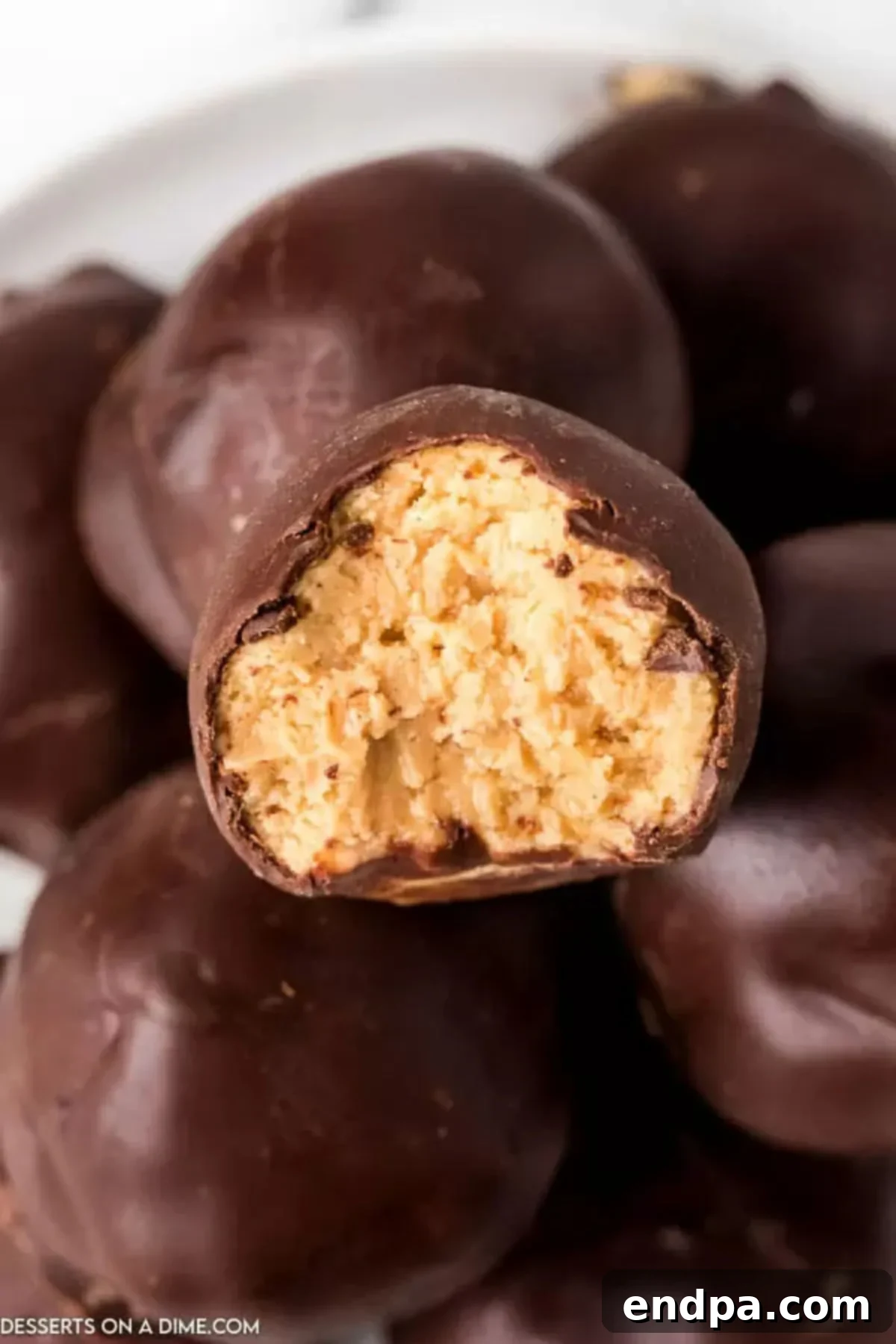 Decadent Chocolate Peanut Butter Bites 2 Stacked homemade chocolate covered peanut butter balls on a plate, showcasing their perfect, glossy coating and creamy interior.