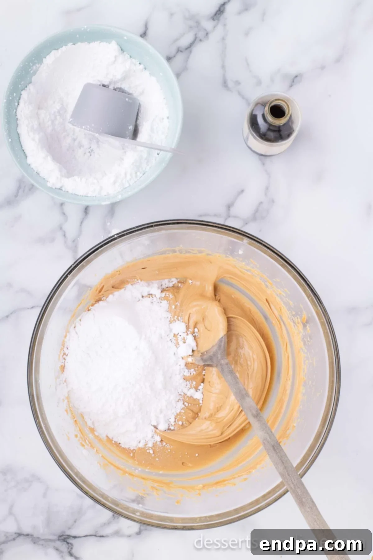 Decadent Chocolate Peanut Butter Bites 4 Powdered sugar being gradually added to the peanut butter and butter mixture in a bowl, showing the start of the mixing process.