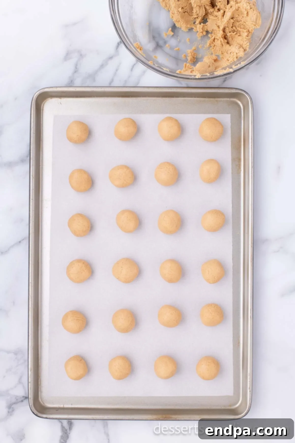 Decadent Chocolate Peanut Butter Bites 6 Perfectly formed peanut butter balls arranged neatly on a baking sheet lined with wax paper, ready for chilling.