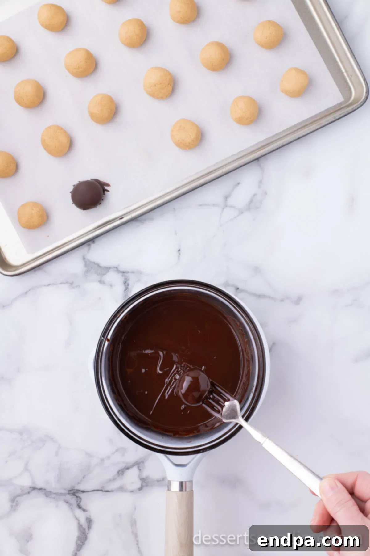 Decadent Chocolate Peanut Butter Bites 7 A peanut butter ball being dipped into a bowl of smoothly melted chocolate, ensuring a full and even coating.