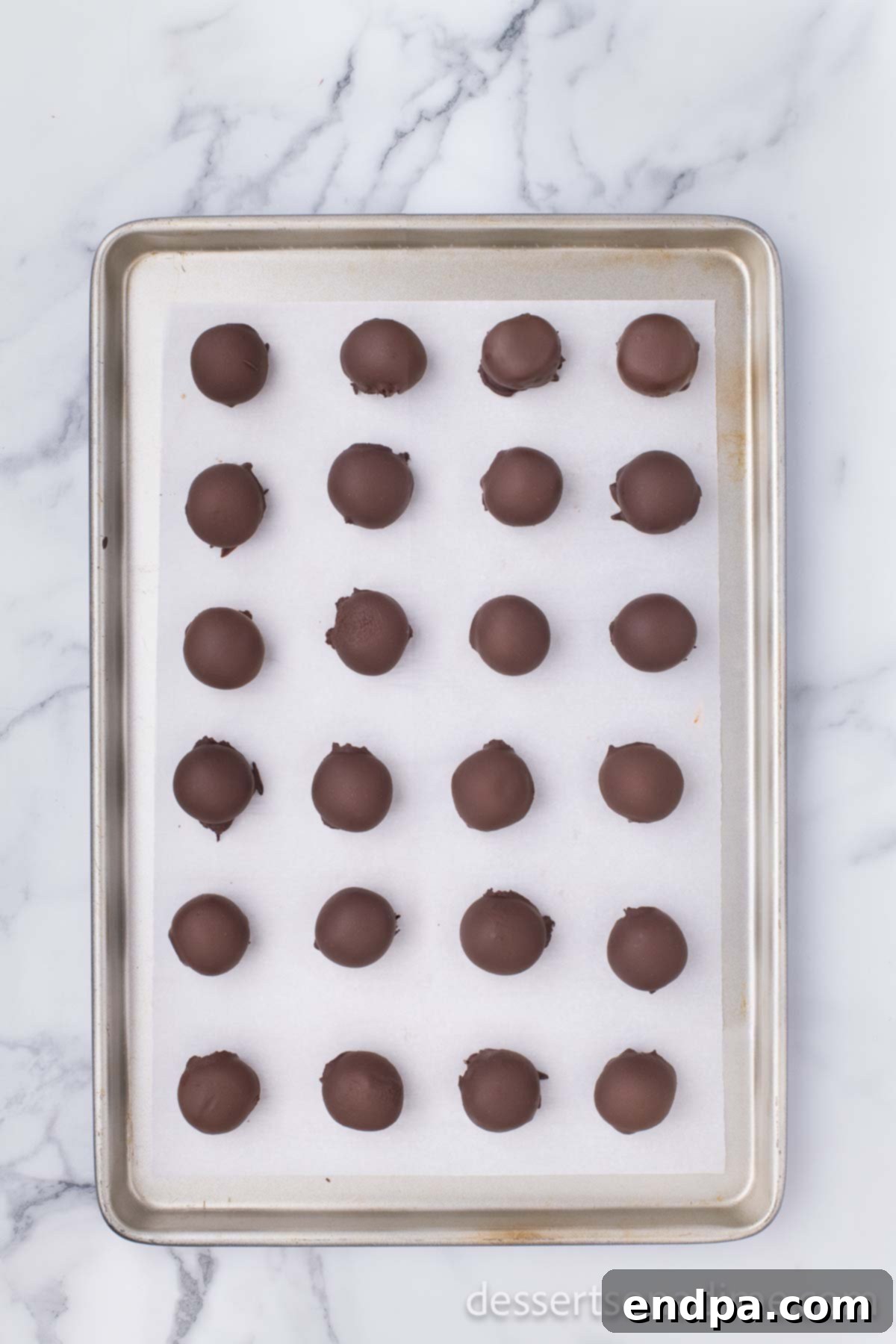 Decadent Chocolate Peanut Butter Bites 8 Freshly chocolate-coated peanut butter balls placed back on the wax paper-lined baking sheet, allowing the chocolate to set.