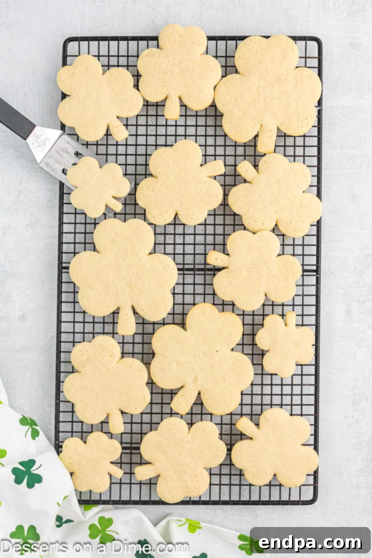 Emerald Clover Delights 10 Warm, freshly baked shamrock cookies cooling on a wire rack after being removed from the baking sheet.